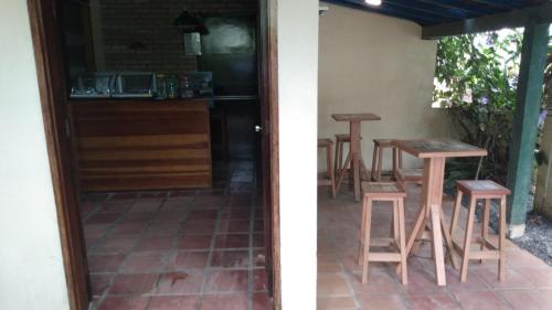 a patio with a table and stools next to a kitchen at Calumar Guest House in Ubatuba