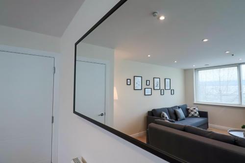 a living room with a couch and a large mirror at Portfolio Apartments - Welwyn Business Park in Welwyn Garden City