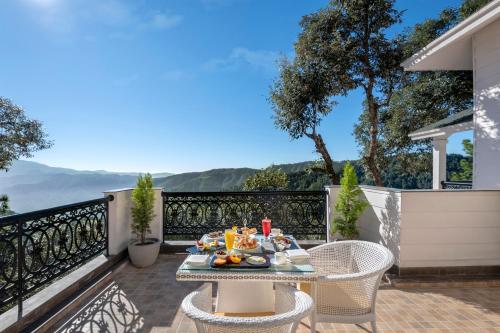 a table with food on top of a balcony with a view at Welcomhotel by ITC Hotels, Tavleen, Chail in Chail
