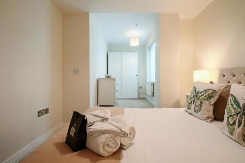 a bedroom with a white bed with a bag on it at Portfolio Apartments - Welwyn Business Park in Welwyn Garden City