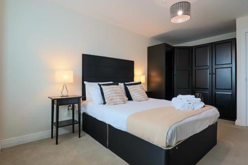 a bedroom with a large bed with a black headboard at Portfolio Apartments - Welwyn Business Park in Welwyn Garden City