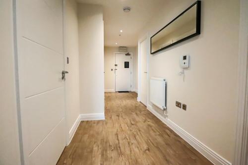 an empty hallway with white walls and wood floors at Portfolio Apartments - Welwyn Business Park in Welwyn Garden City