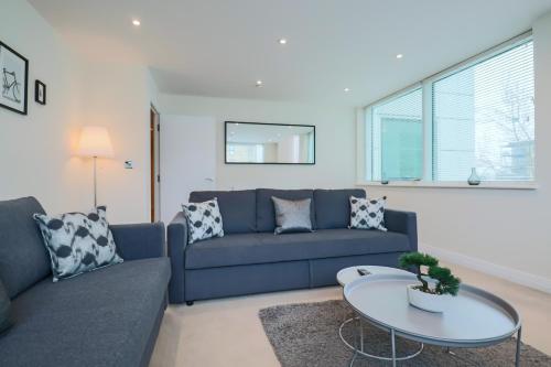 a living room with a blue couch and a table at Portfolio Apartments - Welwyn Business Park in Welwyn Garden City