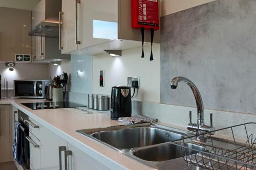 a kitchen with a sink and a counter top at Portfolio Apartments - Welwyn Business Park in Welwyn Garden City