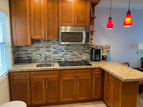 a kitchen with wooden cabinets and a sink and a microwave at Atlantic Shores Vacation Villas in Palm Beach Shores