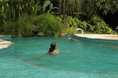 a woman is swimming in a swimming pool at Pousada Tekoá Indiana in Cachoeiras de Macacu