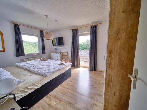 a bedroom with a bed and a large window at Eifel Ferienhaus Mirjam in Manderscheid
