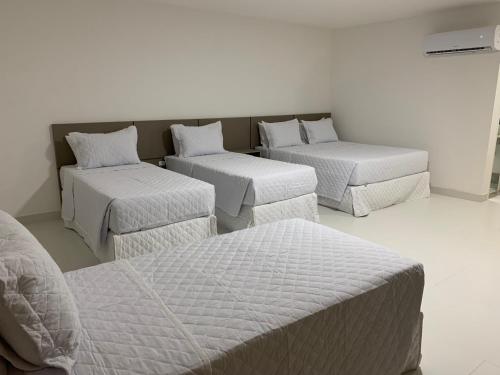 um quarto com três camas e dois repousa-pés em Transcar Suítes em Aracaju