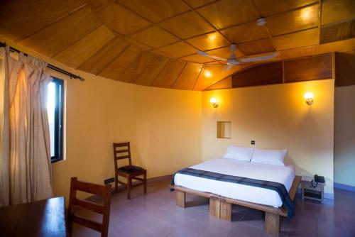 a bedroom with a bed and a wooden ceiling at Le Grand Calao in Ouagadougou