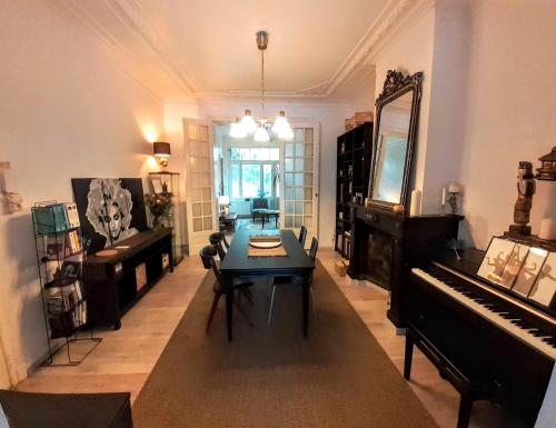 a living room with a table and a piano at Belle Époque Apartment close to EU, NATO & RTBF in Brussels