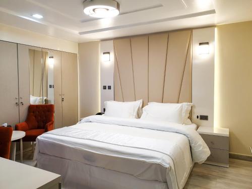 1 dormitorio con 1 cama blanca grande y 1 silla en Musada Luxury Hotels and Suites, en Abuja