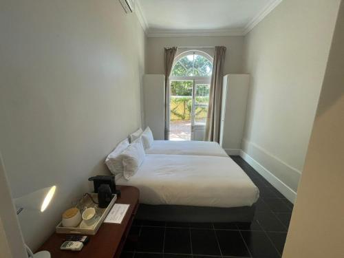 a small room with a bed and a window at De Haas Luxury Living at Villa Grande in Stellenbosch