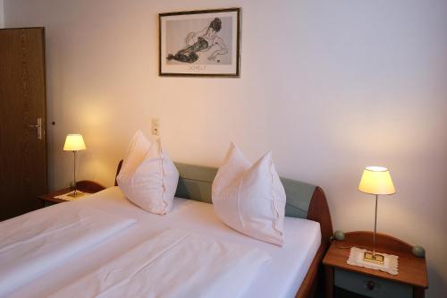 a bedroom with a bed with white sheets and pillows at Ferienwohnungen Berger in Kötschach