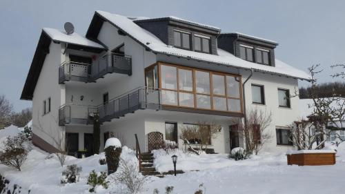 a large white house with snow on the ground at Ferienwohnung Neumann in Gersfeld