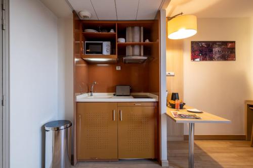 a small kitchen with a sink and a table at Clarion Aparthotel Toulouse Blagnac Airport in Blagnac