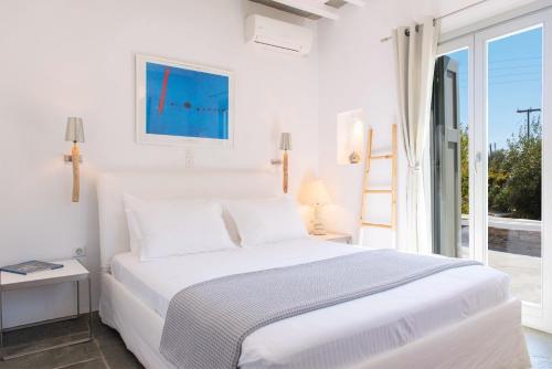 een witte slaapkamer met een bed en een raam bij Villa Arades Sifnos with Private Pool in Apollonia