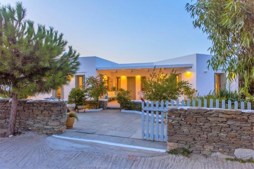 una casa con una valla blanca y una pared de piedra en Villa Arades Sifnos with Private Pool, en Apollonia