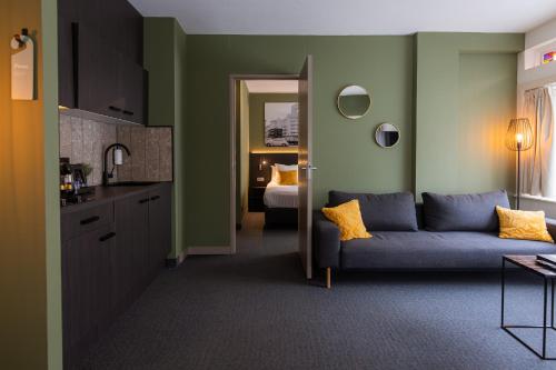 a living room with a blue couch and a kitchen at Hotel Parkzicht Eindhoven in Eindhoven