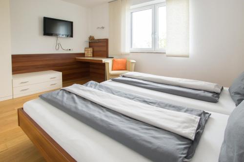 three beds in a room with a desk and a television at Ferienhof Neundlinger in Niederwaldkirchen