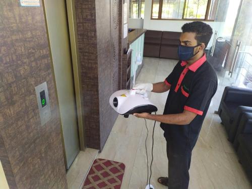 a man wearing a mask holding a machine in a room at Hotel ParkwayInn in Kelambākkam