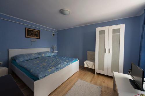 Schlafzimmer mit blauen Wänden, einem Bett und einem Schreibtisch in der Unterkunft Árnyas vendégház, Füge apartman in Balatonboglár