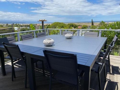 una mesa azul con sillas y jarrones en una terraza en Lasalle holiday home (Sun, Beach, Views, Fun for everyone!), en Plettenberg Bay