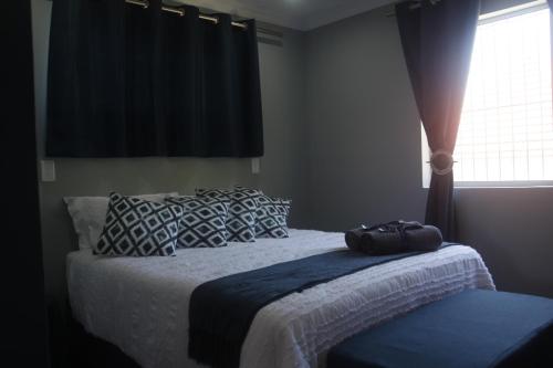 a bedroom with a bed with a bag on it at Aloe Ocean Flatlet in Bettyʼs Bay