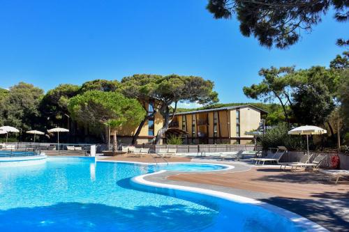 a swimming pool with chairs and umbrellas in a resort at Canado Club Family Village in Marina di Castagneto Carducci