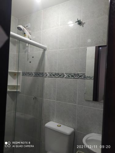 a bathroom with a toilet and a glass shower at RESIDENCIAL CANTINHO PANTANEIRO in Itapoa