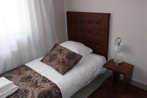 a small bedroom with a bed with a wooden headboard at Belweder in Białystok