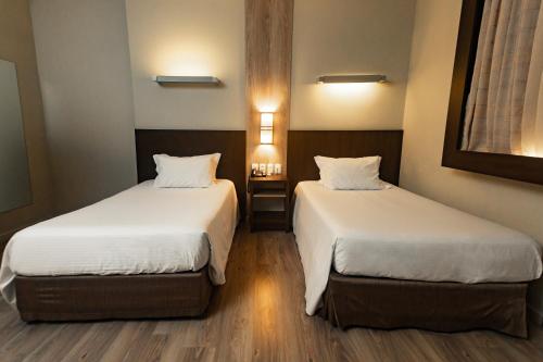 two beds in a hotel room with two beds sidx sidx sidx at Master Cosmopolitan Moinhos de Vento in Porto Alegre