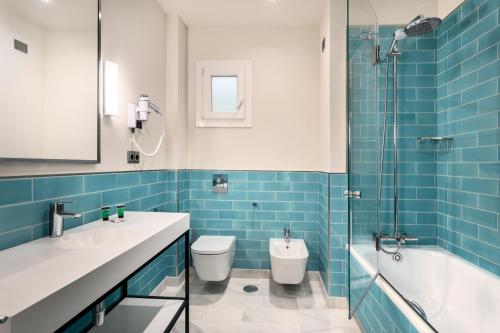 a bathroom with a toilet, sink and tub at Hotel San Pablo Sevilla in Seville