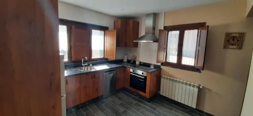 a kitchen with wooden cabinets and a sink at El Rato Apartamentos Rurales in Navia