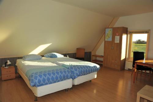 een slaapkamer met een bed, een bureau en een raam bij Witte Weelde Texel in De Koog