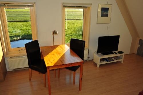 a dining room with a table and chairs and a television at Witte Weelde Texel in De Koog