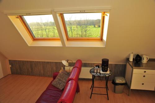 ein Wohnzimmer mit einem roten Sofa und 2 Fenstern in der Unterkunft Witte Weelde Texel in De Koog