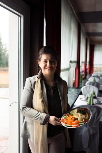 a woman holding a plate of food in a restaurant at Hotel Restaurant Steinhägerquelle in Steinhagen