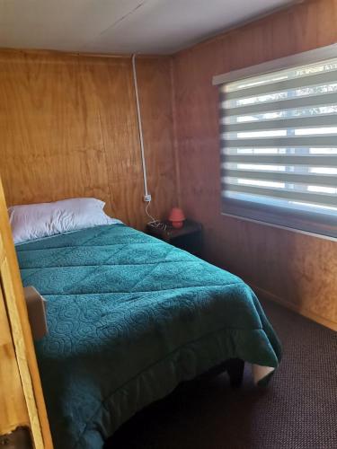Un dormitorio con una cama verde y una ventana. en Cabaña Valle encantado, en Ancud