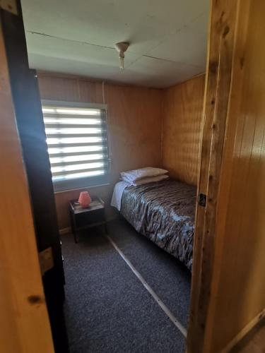 Un dormitorio pequeño con una cama y una ventana. en Cabaña Valle encantado, en Ancud