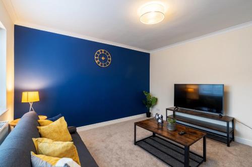 a living room with a blue accent wall at Exceptional 3 bed house with homely comforts, Close to fast food, supermarkets and city centre in Sheffield
