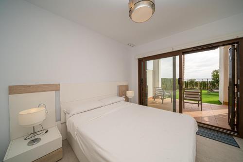 a white bedroom with a bed and a balcony at Linara in San Juan de los Terreros