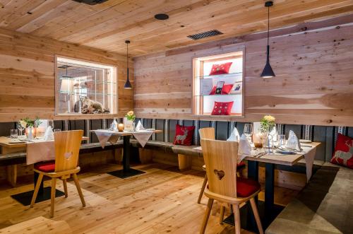 a restaurant with wooden walls and tables and chairs at Tratterhof Mountain Sky Hotel in Maranza