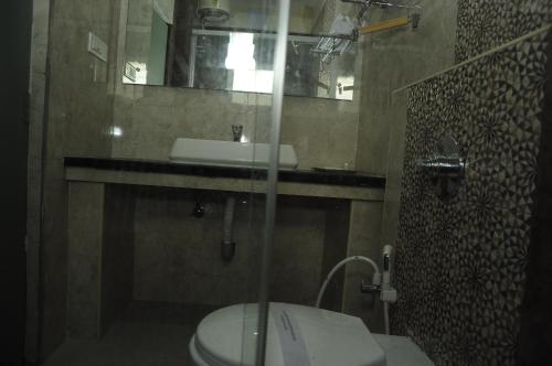 a bathroom with a toilet and a sink and a mirror at Hotel Grand Parkway in Tambaram