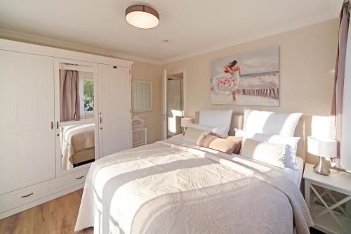 a white bedroom with a large bed and a window at Suite Salzluft mit Sauna in Zingst