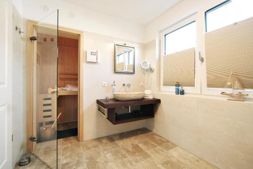 a bathroom with a sink and a glass shower at Suite Salzluft mit Sauna in Zingst