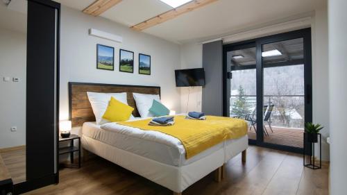 a bedroom with a large bed with a yellow blanket at Apartamenty Sun & Snow Siedlisko Palenica in Ustroń