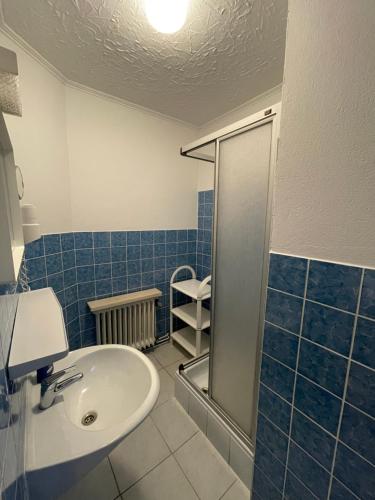 a blue tiled bathroom with a sink and a shower at Ferien- & Monteurzimmer Markhausen in Friesoythe