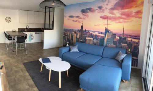 - un salon avec un canapé bleu et une vue sur la ville dans l'établissement Magnifique T3 en plein coeur de Lorient, dernier étage avec balcon terrasse, à Lorient