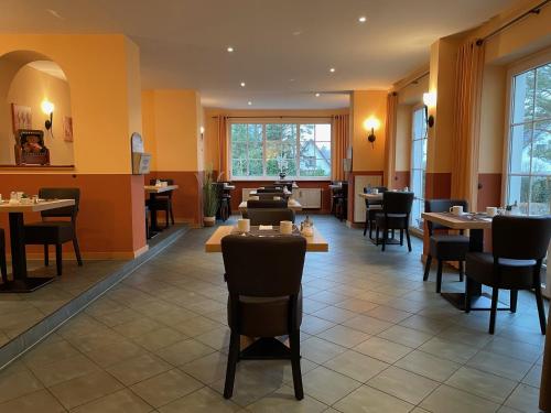 ein Restaurant mit Tischen, Stühlen und Fenstern in der Unterkunft Hotel Villa Strandkorb in Graal-Müritz