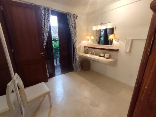 a bathroom with a sink and a mirror and a chair at Monkey Casa Hotel in Trancoso